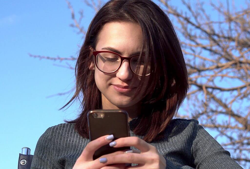 Young Woman Smiling at Phone on Wheelchair